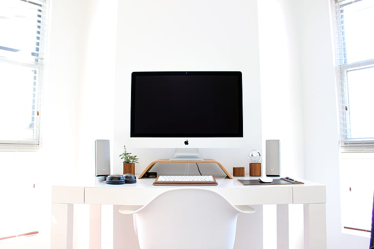 silver iMac beside Apple Keyboard on white wooden table
