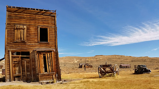 brown shack near brown grass field and wagons