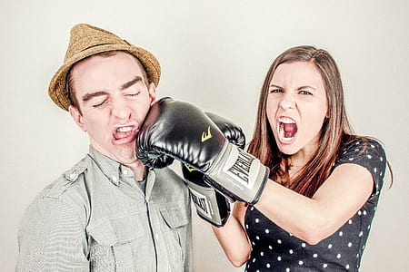 woman wearing black Everlast boxing gloves beside man wearing brown fedora hat