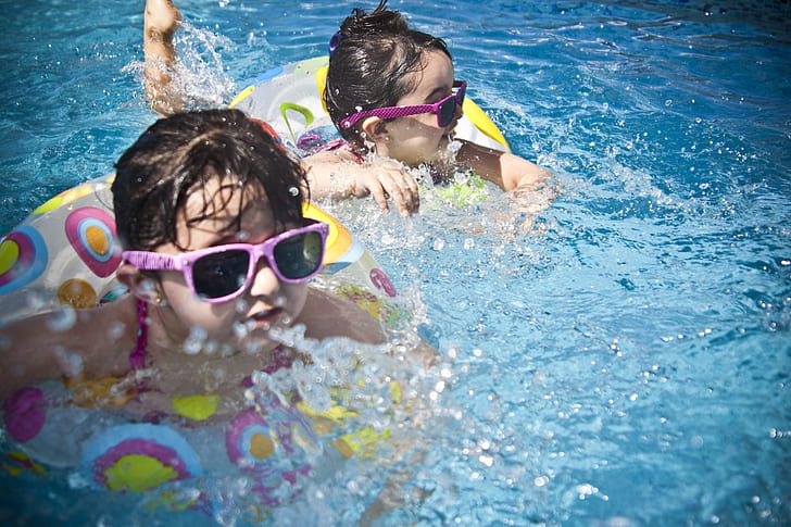 two boy and girl with pink sunglasses swimming