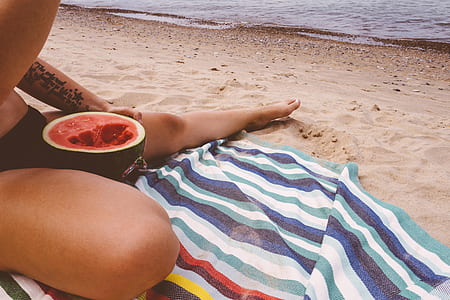 person sitting on seashoe eating melon