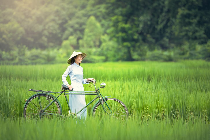 woman wearing brown hat while holding bike