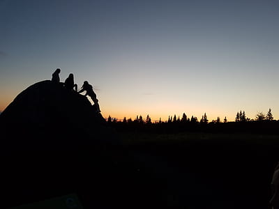 silhouette photo of three person sitting on dome