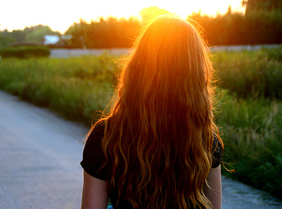 woman wearing black shirt standing on road during golden hour