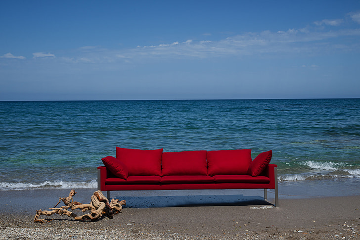 red 3-seat couch near body of water