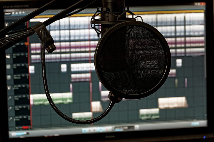 black studio condenser microphone in front of computer monitor