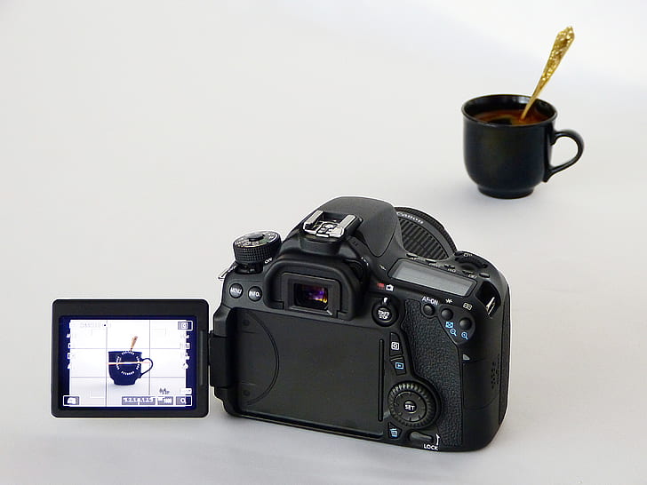 black DSLR camera capturing black ceramic mug with gold-colored spoon
