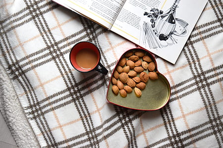 heart-shaped tray with nuts beside mug with coffee