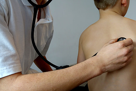 person wearing white polo shirt using stethoscope checking boy back