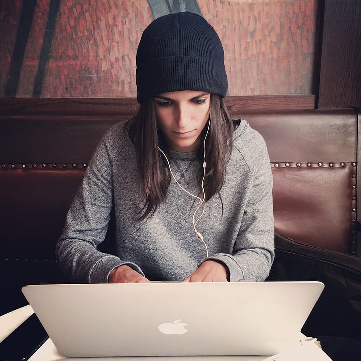 woman wearing black knit cap leaning MacBook