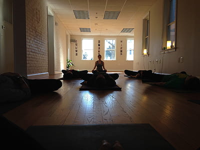 silhouette of people doing yoga inside brown wooden floor room