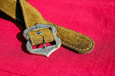 brown leather belt on pink textile