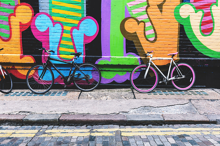 Bicycles stand against a street-art covered wall in the city