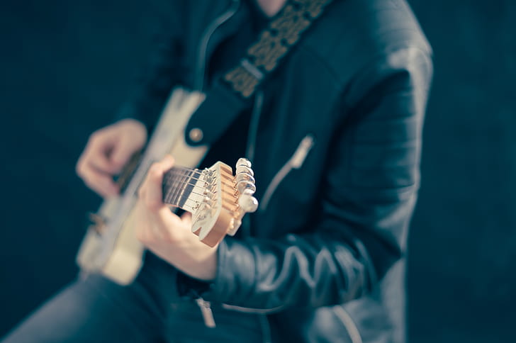man playing guitar wearing black leather jacket