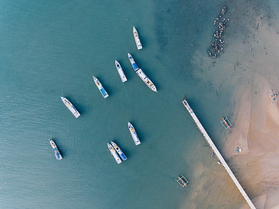 aerial photography of 10 yacht sailing on green ocean near seashore