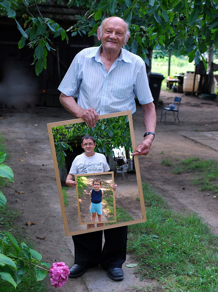photo of man holding photo of man wearing white shirt holding photo frame