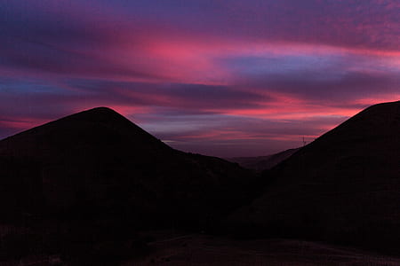 silhouette of hill under pink and gray sky