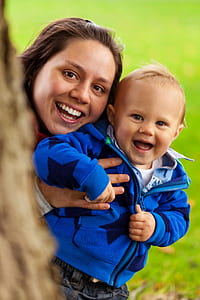 woman holding baby in blue zip-up hoodie focus photo