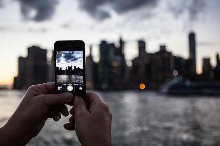An iPhone mobile smartphone user captures the Manhattan skyline from DUMBO in Brooklyn, New York City