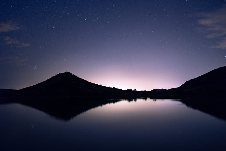 silhouette photo of mountain reflecting body of water