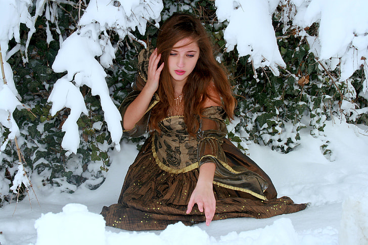 woman in green floral dress about to reach snow under snow covered green leaf plant