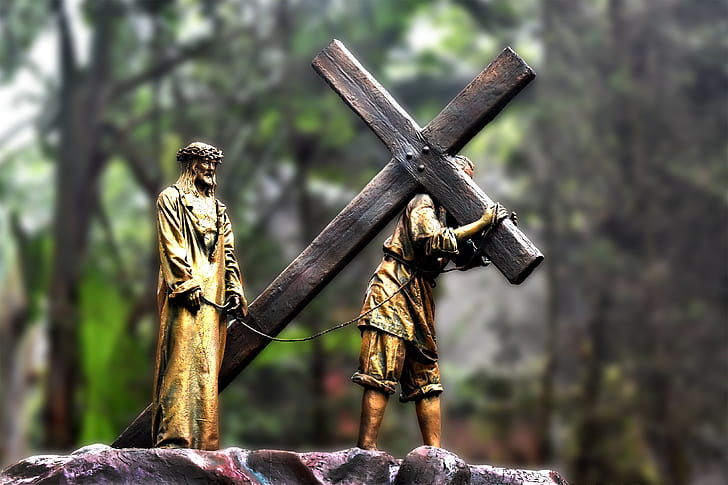 person carrying cross near man standing figurines