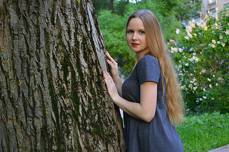 woman wearing gray shirt leaning on tree