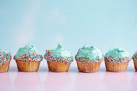 six lined up green cupcakes topped with sprinkles