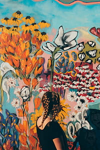 woman wearing black t-shirt facing wall full of flower paint