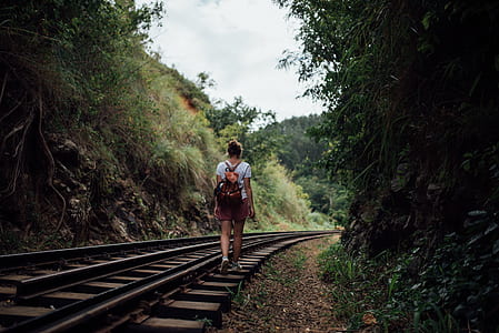 woman wearing white t-shirt walking on train trail during daytime