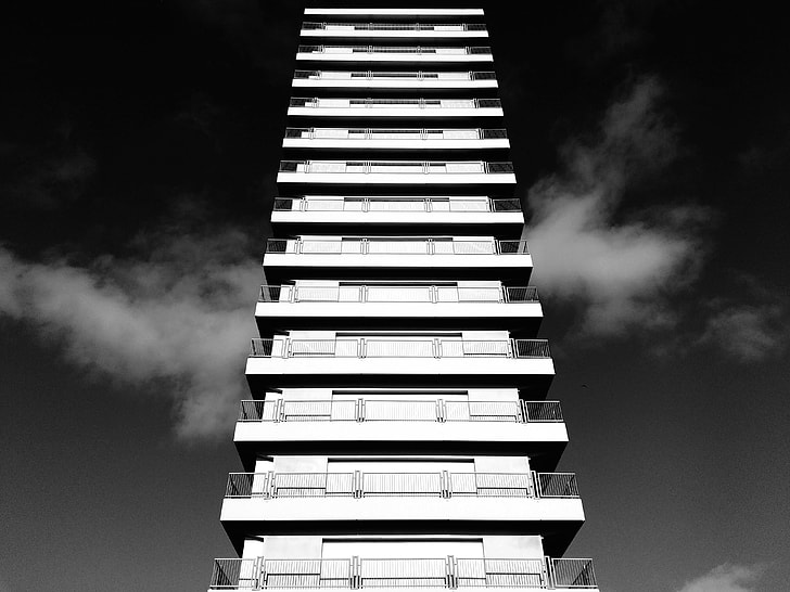 white concrete high rise building on sunny day grayscale photo