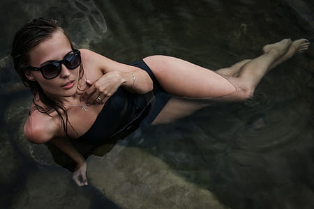 woman black bodysuit with black sunglasses with black frames on body of water