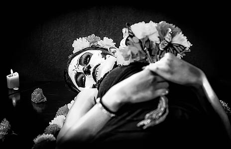 grayscale photo of woman lying while holding flowers