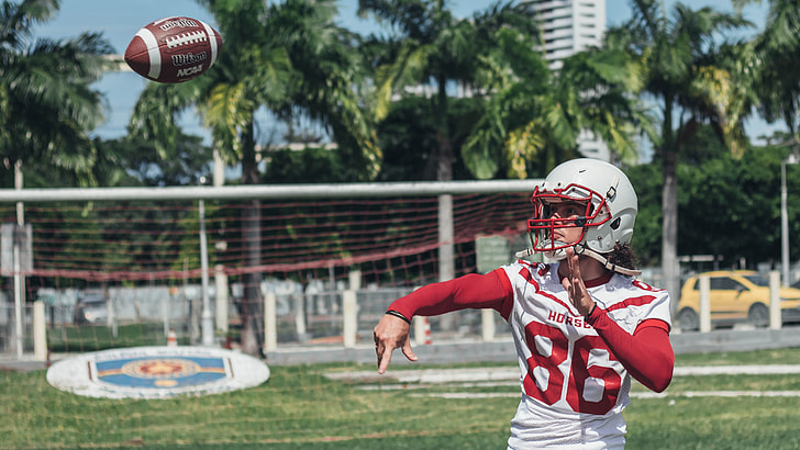 man wearing red and white 86 football jersey throwing football