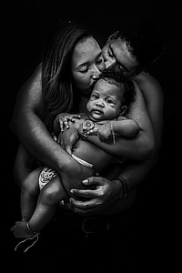 man and woman hugging baby grayscale photo