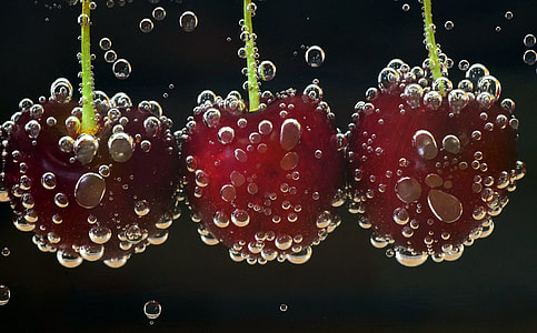 three red cherries dipped on carbonated water
