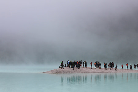 people standing on gray surface on body of water photography