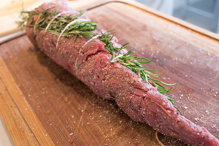 preparing meat with rosemary, salt and pepper