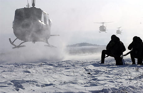 two person kneeling beside helicopter land on snow field