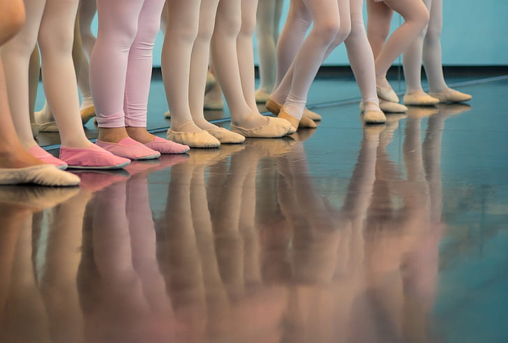 ballerinas wearing leggings and shoes reflecting on wood floor