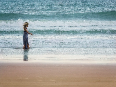 woman walking on seashore during daytime