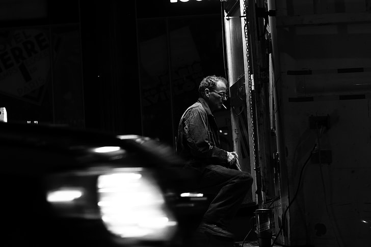 grayscale photo of man sitting while smoking