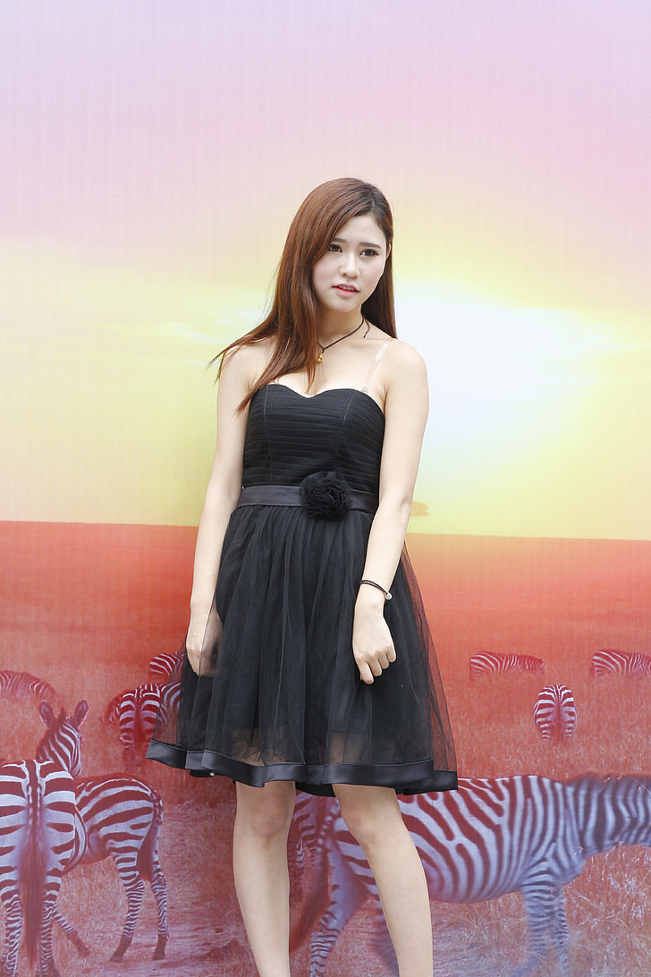 woman wearing black sweetheart neckline mini dress standing near wall with zebra digital wallpaper
