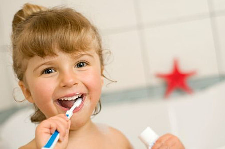 toddler girl brushing her teeth and holding toothpaste soft-tub