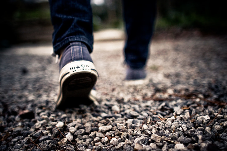 photo of person walking wearing Converse shoes