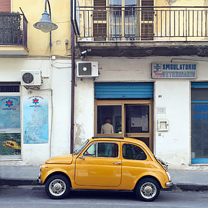 yellow Volkswagen beetle parked near establishment during daytime
