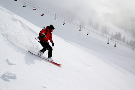 man wearing black and red suit doing snowboarding during daytime