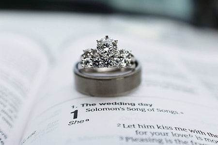 silver-colored band ring on top of white book with The Wedding Day song lyrics
