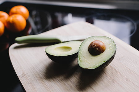 avocado fruit on chopping board beside green handled knife