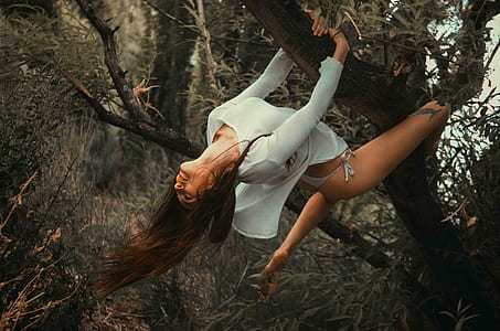 woman wearing white bikini bottoms climbing on tree